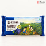 A 500 g package of Byond Blueberry Flavoured Compound Baking Powder, featuring a dark blue wrapper with an illustration of a blueberry field and workers picking blueberries.