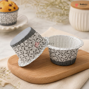 Patterned paper cupcake liners on a wooden board with a muffin in the background.