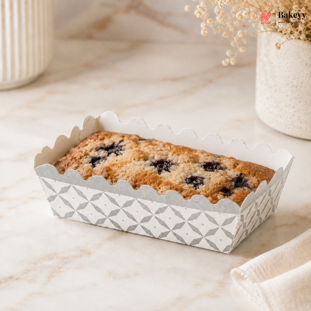 Loaf of bread in a decorative paper container on a marble surface with 'Bakey' branding.