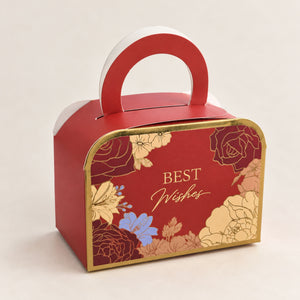 A red gift box with a curved handle, decorated with gold floral illustrations and the words 'BEST Wishes' on the front, set against a plain light beige background.