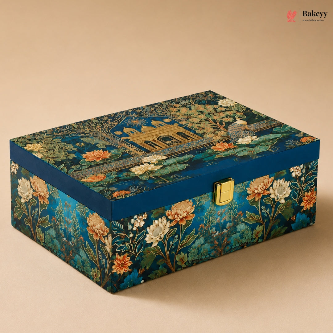 A rectangular decorative box with a blue floral and architectural print, featuring a gold clasp on the front, photographed on a beige background.