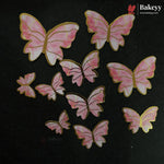 Pink and white marbled butterfly-shaped embellishments with gold borders, arranged on a black background. The Bakeyy brand logo is visible in the top right corner.