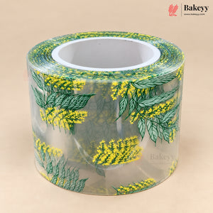 A roll of clear adhesive tape featuring a repeating pattern of green leaves and yellow flowers, displayed on a neutral beige background with a Bakeyy brand logo in the top right corner.