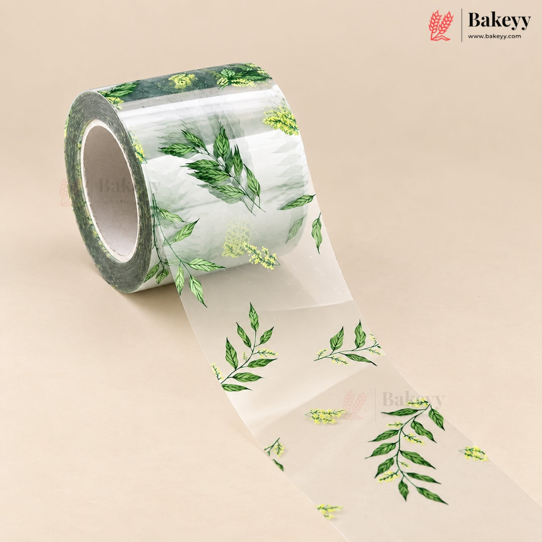 A roll of clear decorative tape with a green leaf and small yellow floral print, shown on a beige background with the Bakeyy brand logo in the top right.