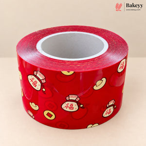 A roll of red decorative tape featuring traditional Chinese motifs including gold Chinese coins, red envelopes with Chinese characters, and a small straw hat, photographed on a neutral beige background.