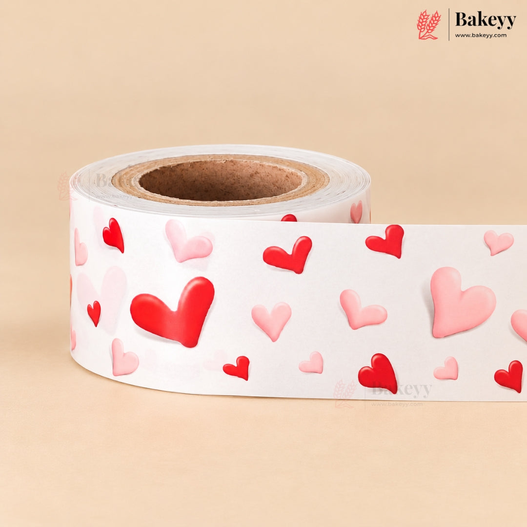 A roll of white bakery tape featuring a pattern of red and pink 3D-effect hearts, displayed on a warm beige background with the Bakeey brand logo in the top right corner.