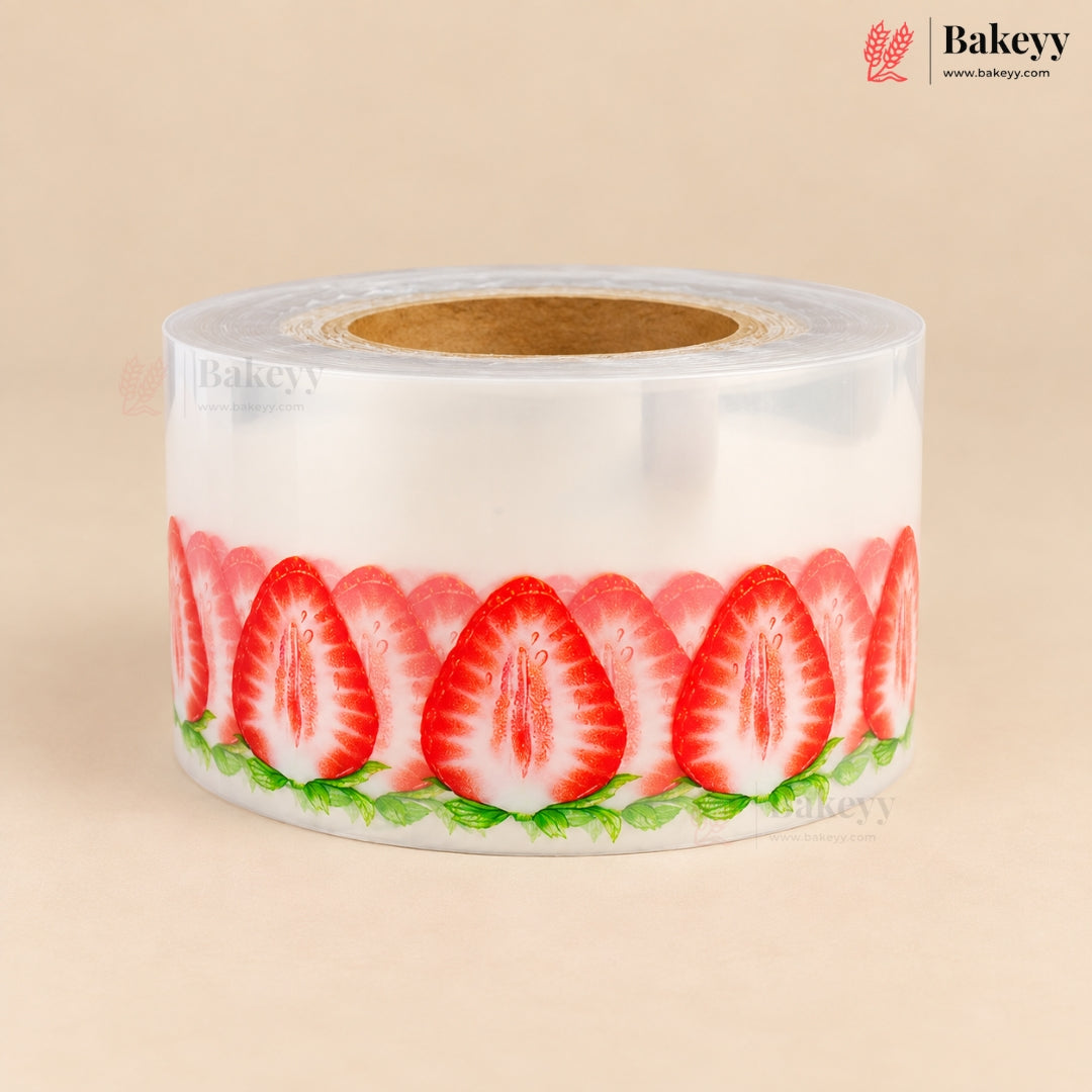 A roll of clear plastic stretch wrap featuring a printed pattern of sliced red strawberries with green leaves, shown on a beige background.