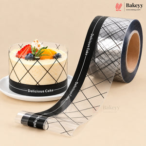 A roll of clear bakery tape with a black grid pattern and white 'Delicious Cake' text, shown next to a decorated cake on a white plate. The Bakeyy brand logo is visible in the top right corner.