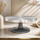 Cake stand on a marble surface with decorative elements and 'Bakeyy' branding.