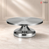 Metallic cake stand on a beige background with 'Bakeyy' branding.