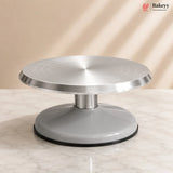 Silver cake turntable on a marble surface with a beige background