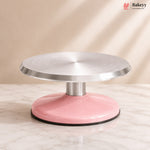 Pink and silver cake turntable on a beige background with 'Bakeyy' branding.