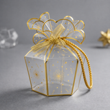 Clear gift box with gold decorative bow on a gray background