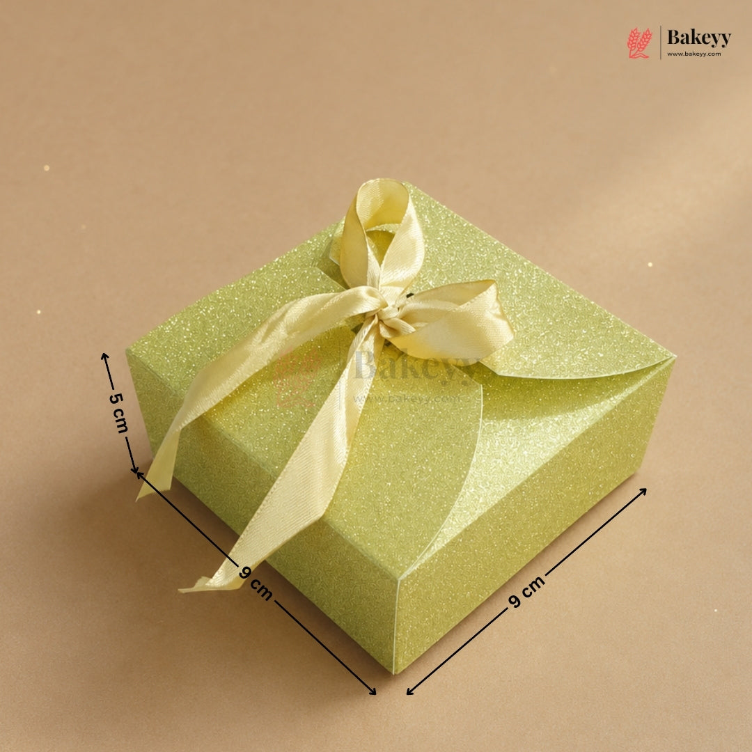 Green gift box with a yellow ribbon on a beige background, featuring dimensions.