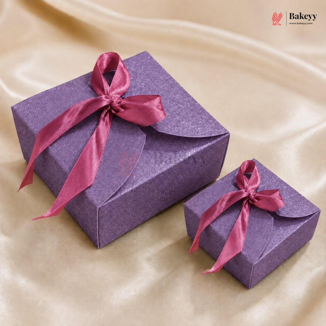 Two purple gift boxes with red ribbons on a beige fabric background, featuring the Bakey brand.