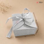 Silver gift box with a ribbon on a beige background, featuring dimensions.