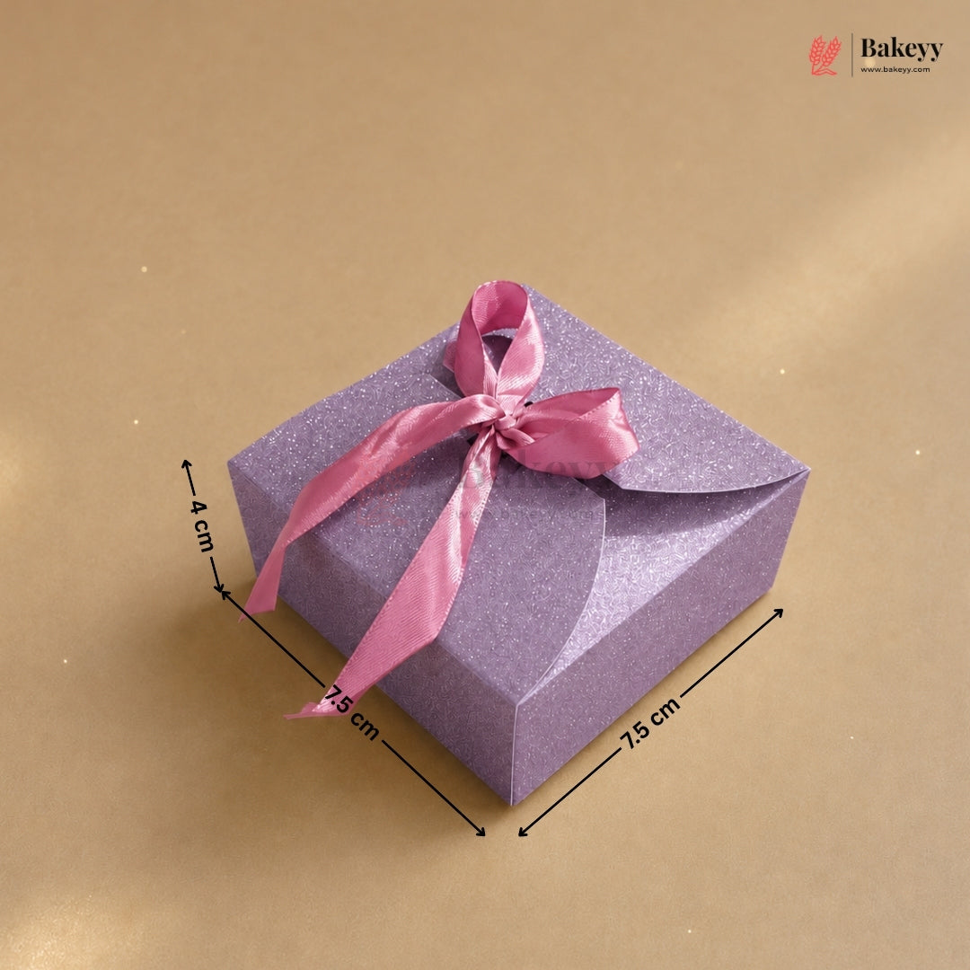 Purple gift box with a pink ribbon on a beige background, featuring dimensions.