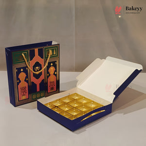 A blue and gold bakery gift set including an open box of individually wrapped pastries and a matching decorative gift bag, displayed on a neutral light gray background.