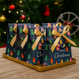 Christmas-themed gift boxes with ribbons on a tray in front of a decorated Christmas tree.