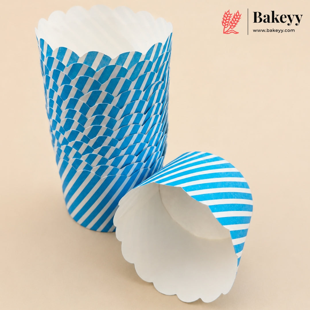 Blue and white striped paper cupcake liners, with one liner standing upright and another lying on its side to show the white scalloped inner lining, on a beige background. A Bakeyy brand logo is visible in the top right corner.
