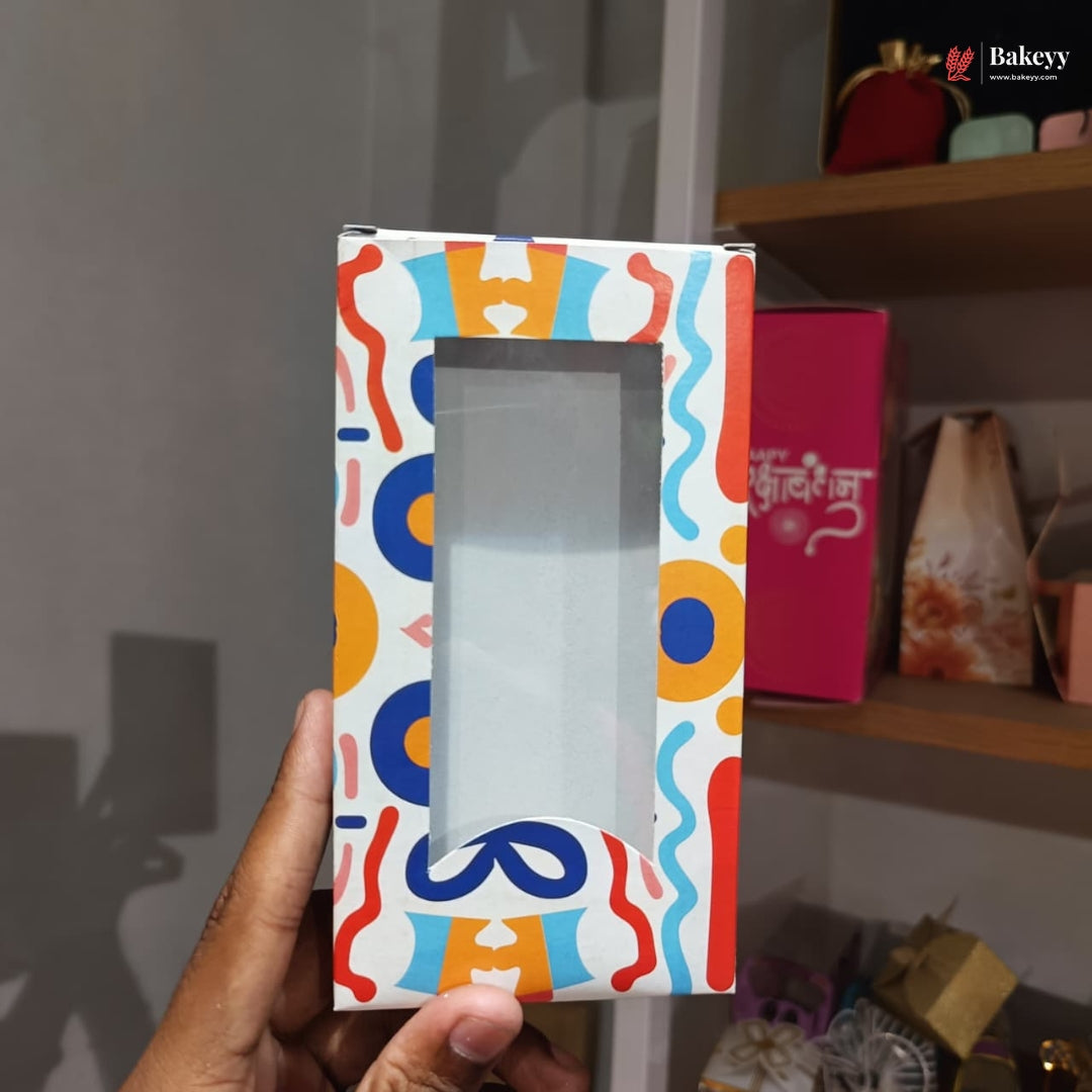 Colorful gift box with a clear window held by a hand against a blurred background