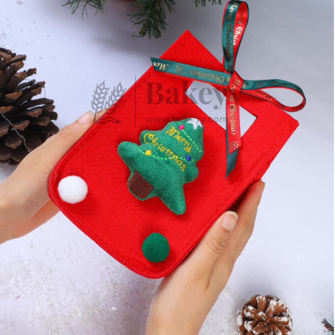 Red pouch with Christmas tree design held by a hand, surrounded by pine cones on a light background.