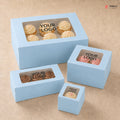 Set of light blue cake boxes with windowed tops on a beige background