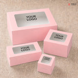 Set of pink boxes with windowed top and 'YOUR LOGO' label on a beige background