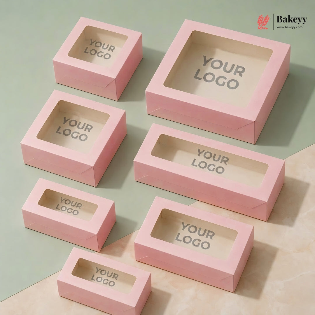 Pink cake boxes with 'YOUR LOGO' text on a light green and beige background, featuring the Bakeyy brand.