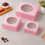 Three pink boxes with 'YOUR LOGO' text on a light gray surface with berries and flowers.
