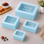 Set of light blue boxes with 'YOUR LOGO' text on a neutral surface with fruits and a plant.