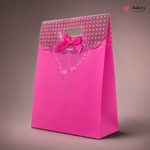 Pink gift bag with gold polka dots and a bow on a brown background