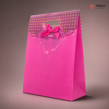 Pink gift bag with gold polka dots and a bow on a brown background