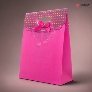 Pink gift bag with gold polka dots and a bow on a brown background