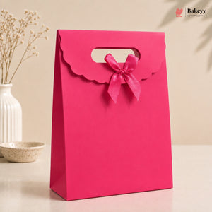 Pink gift bag with a bow on a beige background, featuring the Bakeyv brand.