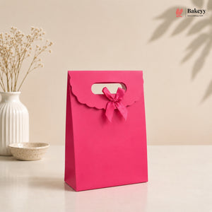 Pink gift bag with a bow on a beige background, featuring the brand 'Bakey'.