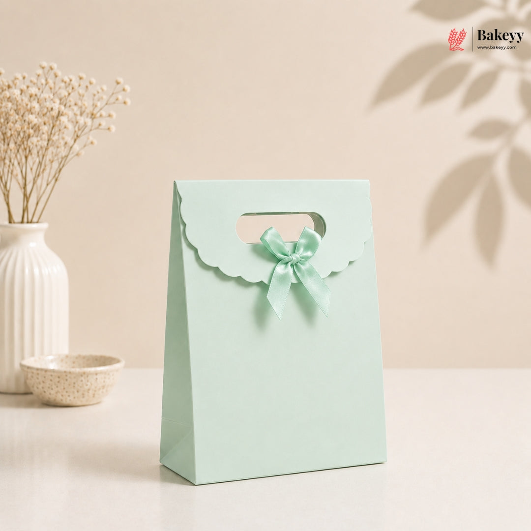 Light blue gift bag with a bow on a beige background, featuring the brand 'Bakeyy'.
