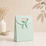 Light blue gift bag with a bow on a beige background, featuring the brand 'Bakeyy'.