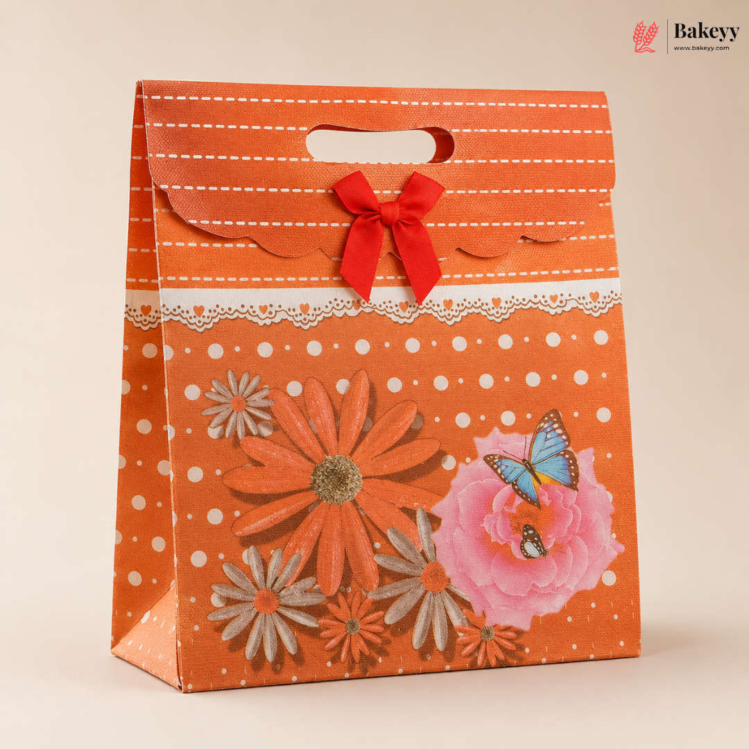 Decorative orange gift bag with floral designs and a red bow on a beige background