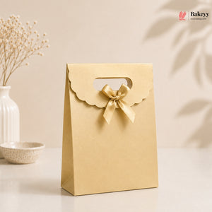 Gold gift bag with a bow on a light background, featuring the brand 'Bakeyy'.