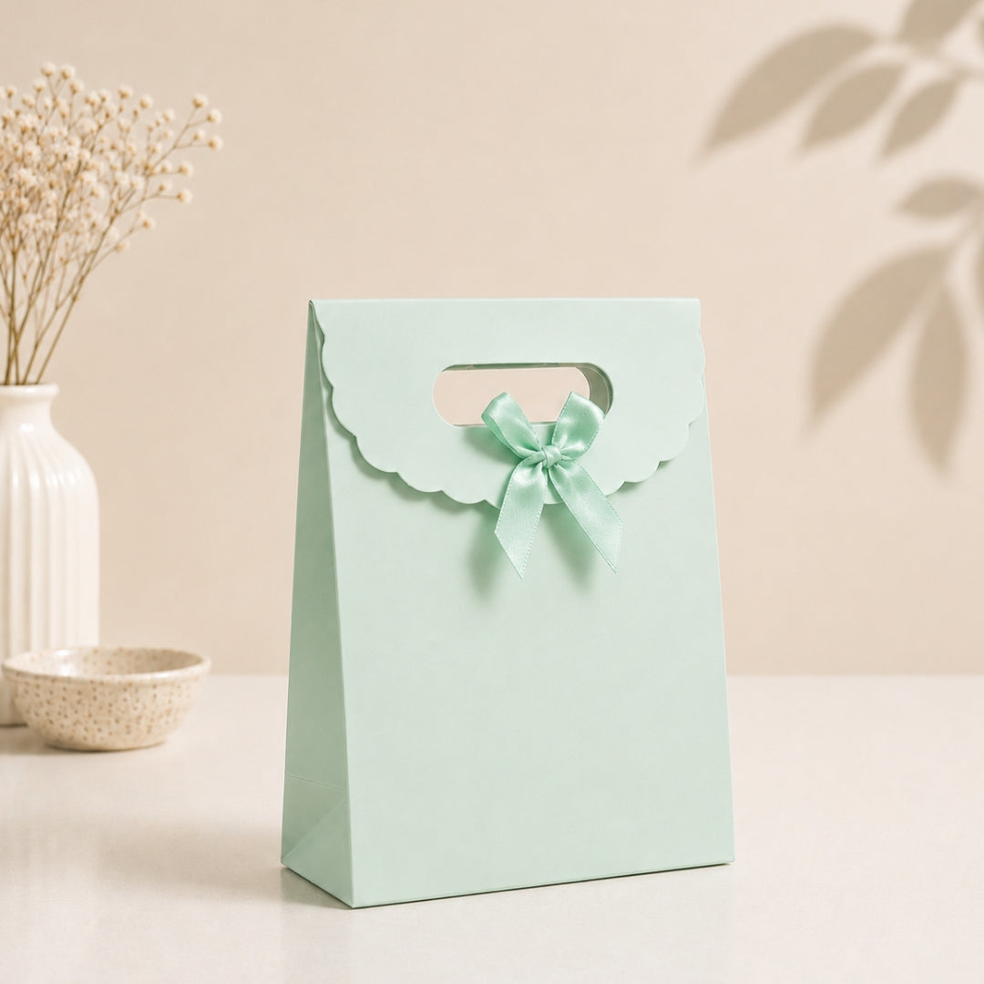 Mint green gift bag with a bow on a light beige background