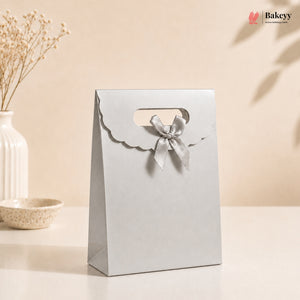 White gift bag with a bow on a beige background, featuring the Bakey brand.