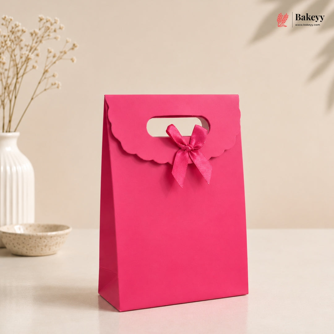 Pink gift bag with a bow on a beige background, featuring the Bakey brand.