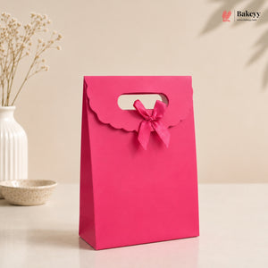 Pink gift bag with a bow on a beige background, featuring the Bakey brand.