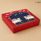 A square red gift box with a lid featuring a detailed illustration of two white cows with pink lotus flowers on a beige background.