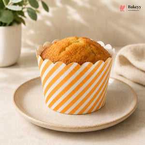 Muffin in a striped paper cup on a plate with a plant and towel in the background