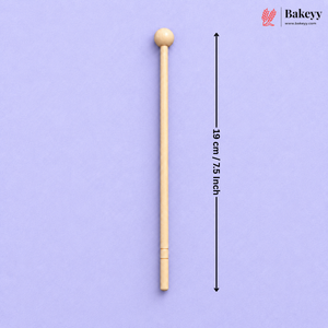 A single wooden cake turner with a round ball handle is shown vertically on a light purple background, with a black dimension arrow and text indicating a height of 19 cm / 7.5 inch.