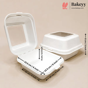 Two white biodegradable square cake boxes on a beige background, with one closed and one open containing a small birthday cake. The Bakeyy logo is visible in the top right corner.