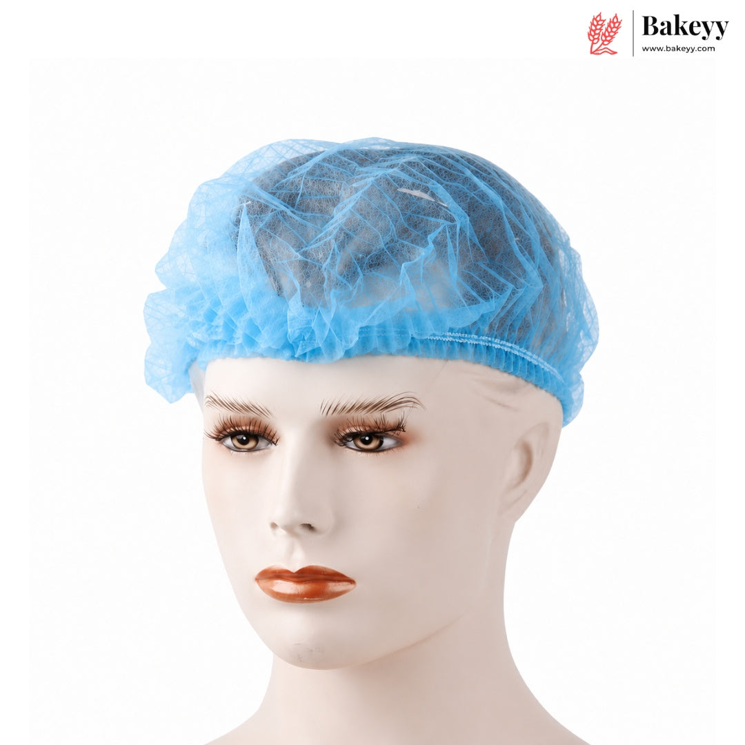 A light blue disposable non-woven bakery cap shown on a mannequin head against a plain white background, with the Bakeyy logo in the top right corner.