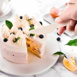 Slice of cake being lifted from a decorated cake with blueberries and cream.